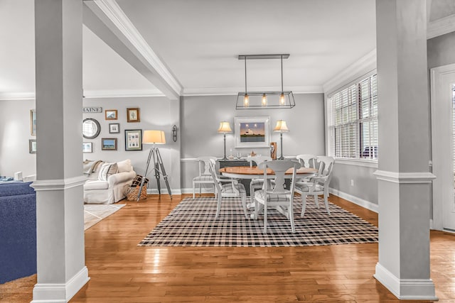 dining space with light hardwood / wood-style floors, crown molding, and decorative columns