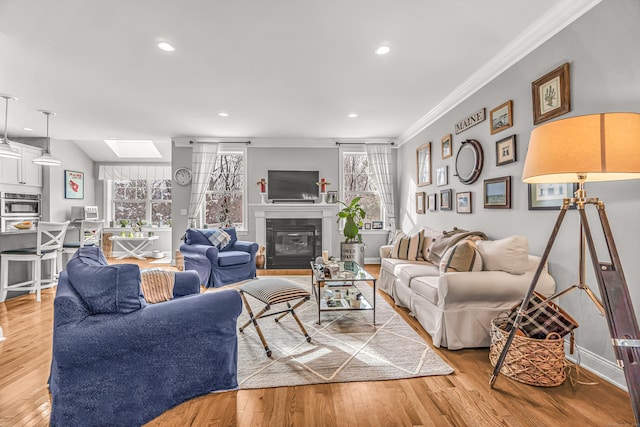 living room featuring light hardwood / wood-style flooring, a wealth of natural light, a skylight, and ornamental molding