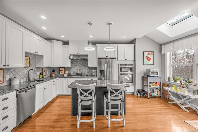 kitchen featuring appliances with stainless steel finishes, sink, white cabinetry, pendant lighting, and a kitchen island