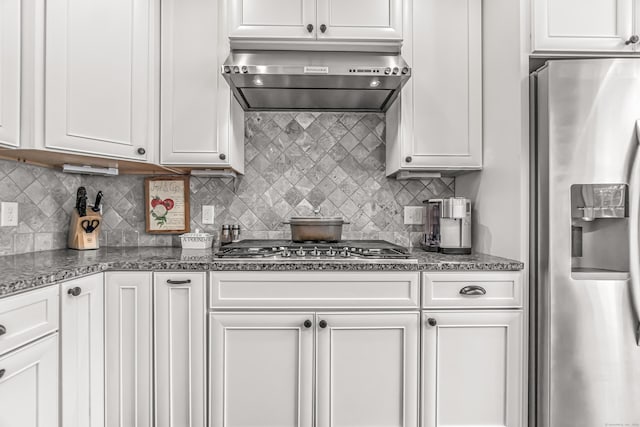 kitchen with appliances with stainless steel finishes, wall chimney range hood, white cabinets, and stone countertops