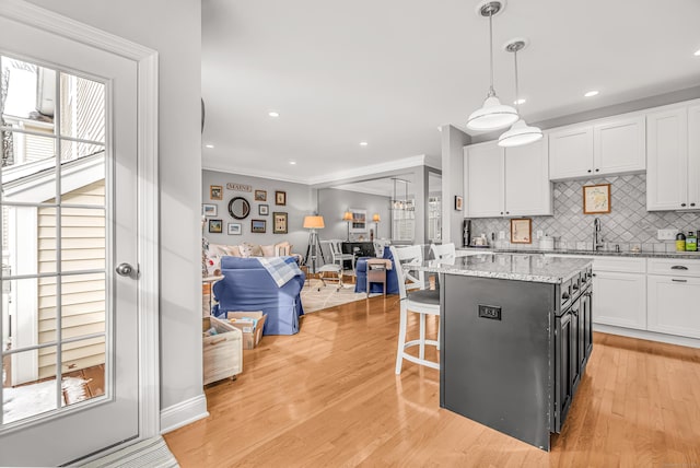 kitchen with white cabinets, decorative light fixtures, a center island, backsplash, and sink