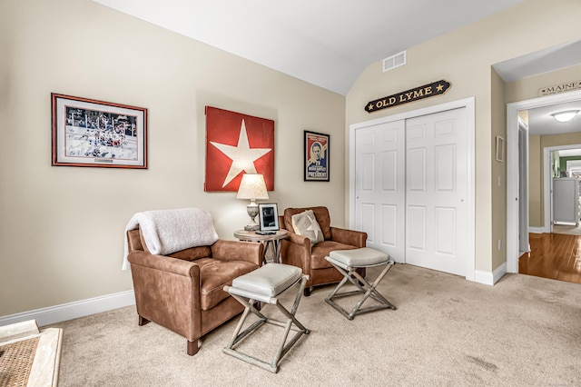 sitting room featuring vaulted ceiling and carpet flooring