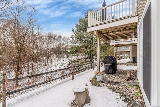 snow covered patio with grilling area and a deck