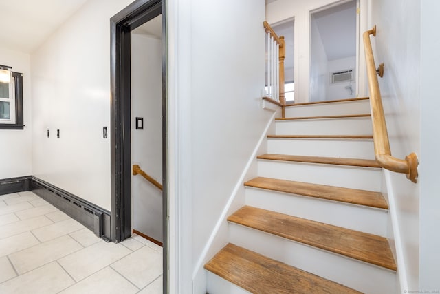 stairs featuring a wall mounted air conditioner, tile patterned flooring, and baseboards