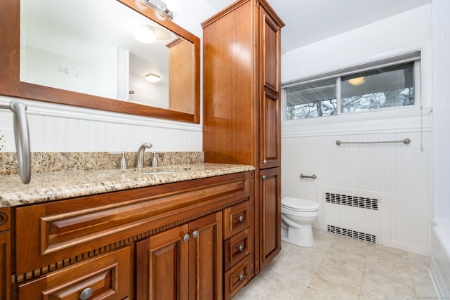 full bathroom with tile patterned flooring, toilet, a wainscoted wall, vanity, and radiator heating unit