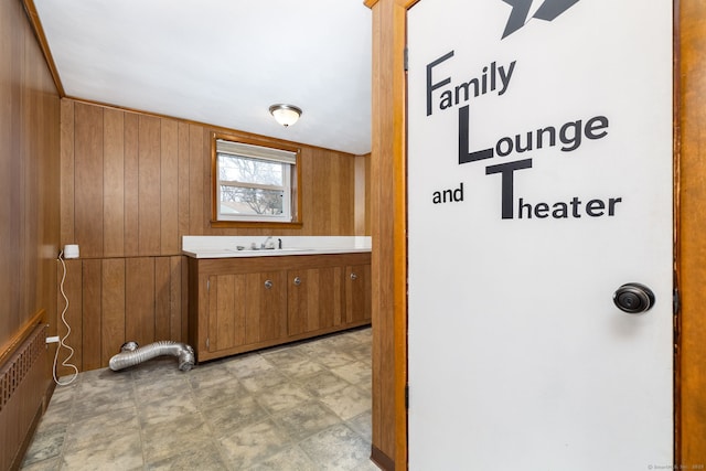 washroom featuring wood walls, radiator heating unit, and a sink