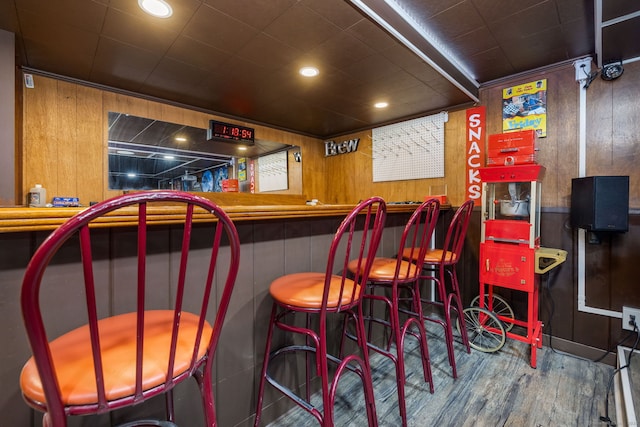 bar featuring a bar, wood walls, wood finished floors, and recessed lighting