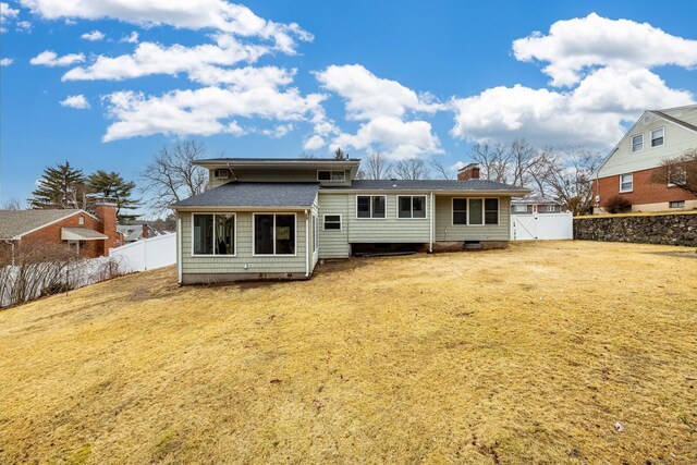 rear view of house featuring a gate, a fenced backyard, a lawn, and a chimney