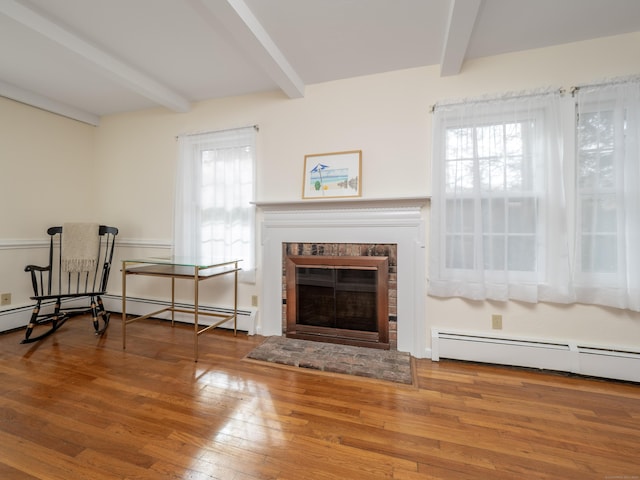 living area featuring a baseboard radiator, a fireplace, beamed ceiling, and hardwood / wood-style floors