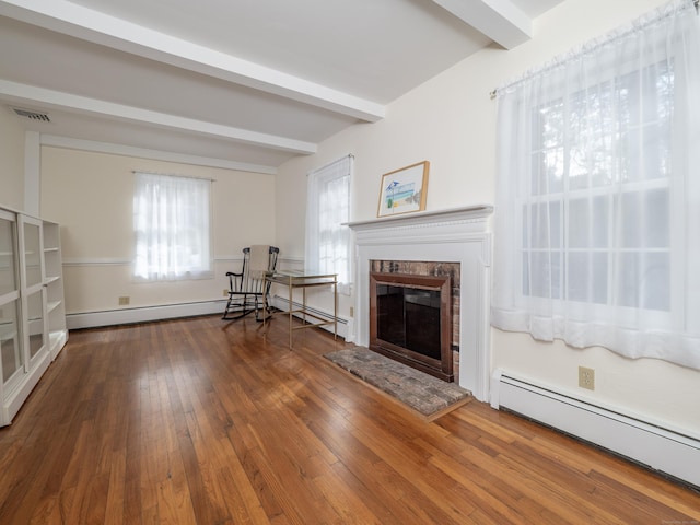 unfurnished room with a baseboard heating unit, visible vents, beam ceiling, wood-type flooring, and a glass covered fireplace