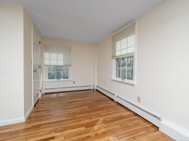 empty room with baseboard heating, baseboards, and light wood finished floors