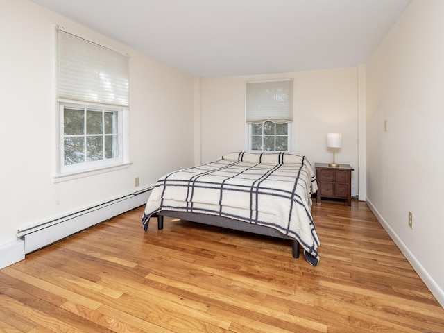 bedroom with light wood-style floors, a baseboard radiator, and baseboards