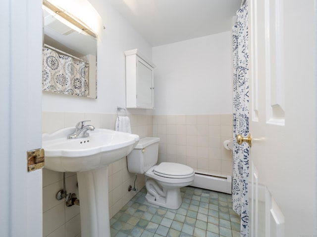 bathroom with toilet, a wainscoted wall, tile patterned floors, baseboard heating, and tile walls