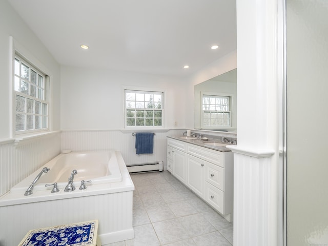 bathroom with a wainscoted wall, double vanity, a baseboard heating unit, a sink, and a bath