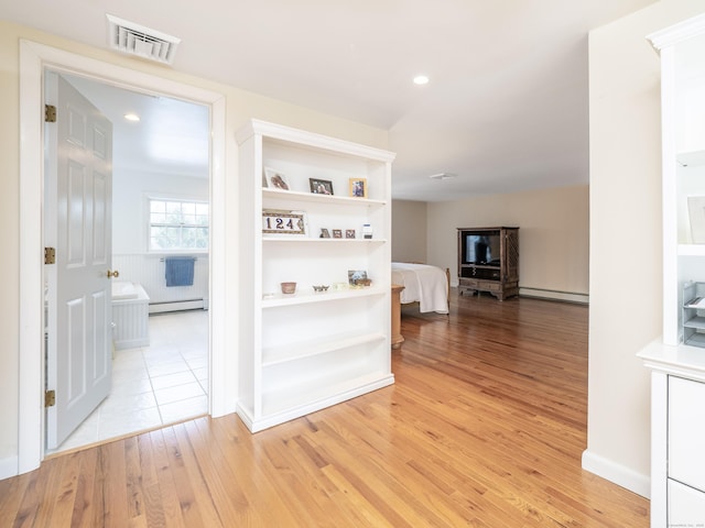 hall featuring light wood-style floors, a baseboard radiator, visible vents, and recessed lighting