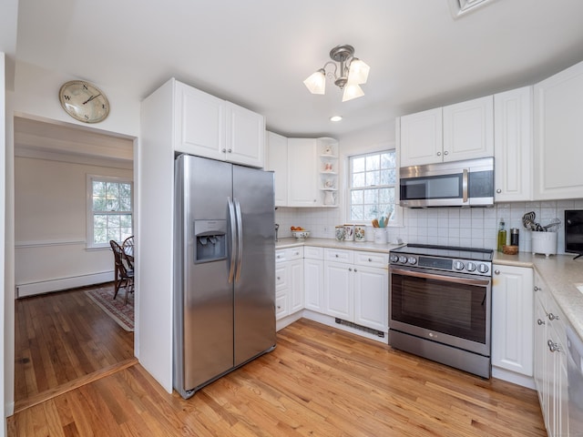 kitchen with white cabinets, a baseboard radiator, stainless steel appliances, and light countertops