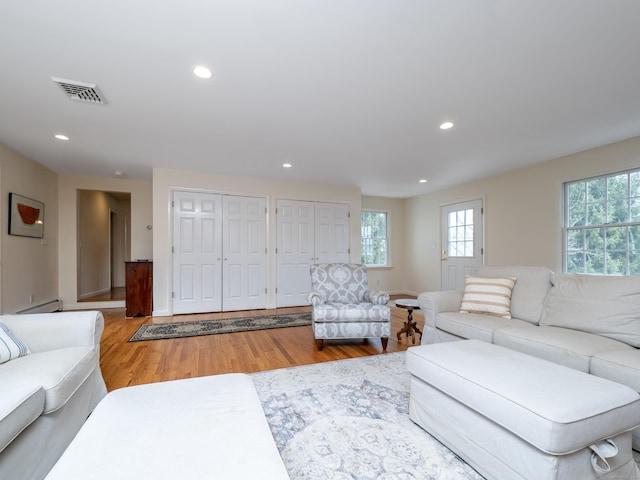 living room with a baseboard heating unit, recessed lighting, visible vents, and wood finished floors