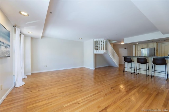 living area featuring stairs, recessed lighting, baseboards, and light wood-type flooring