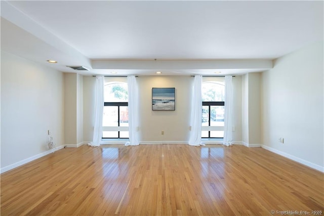 empty room with light wood finished floors, plenty of natural light, recessed lighting, and baseboards