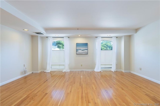 empty room featuring a healthy amount of sunlight, light wood-type flooring, and baseboards