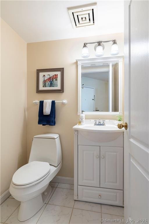 bathroom with marble finish floor, toilet, vanity, and baseboards