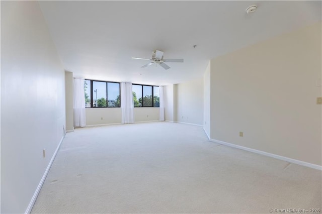 spare room with baseboards, light carpet, and ceiling fan