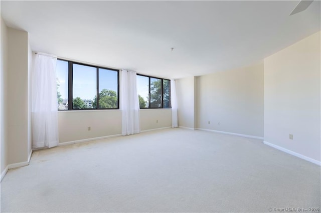 empty room featuring light colored carpet and baseboards