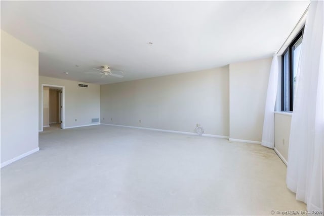 unfurnished room featuring light colored carpet, visible vents, a ceiling fan, and baseboards