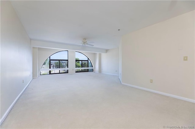 unfurnished room with a ceiling fan, light colored carpet, and baseboards