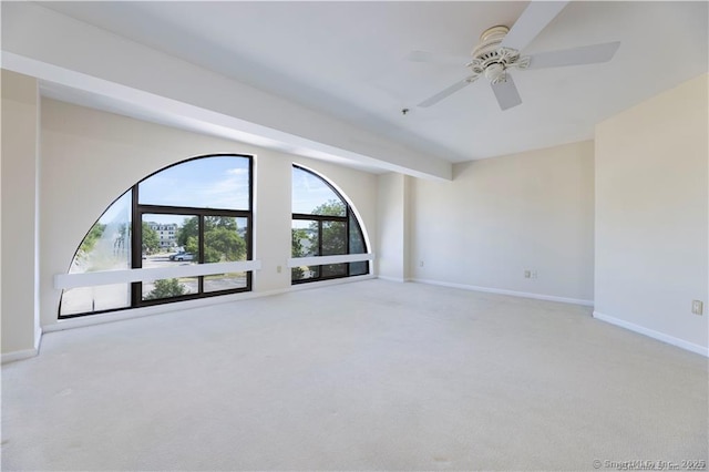 empty room featuring baseboards, carpet floors, beamed ceiling, and ceiling fan