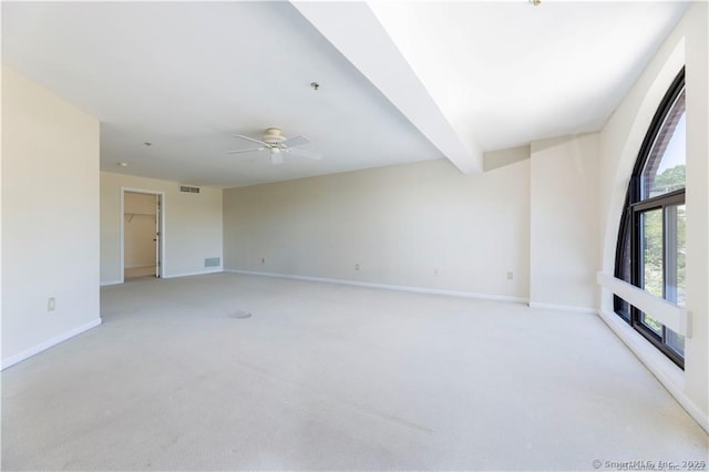 unfurnished room featuring beam ceiling, light colored carpet, baseboards, and visible vents