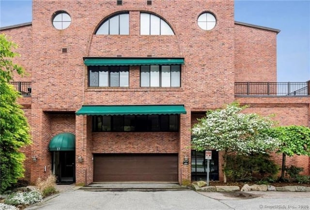 view of front of property featuring brick siding, a garage, and driveway