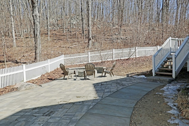 view of patio / terrace with a fenced backyard, stairs, and a view of trees