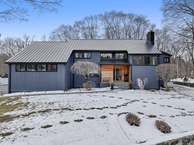 view of front of property with a standing seam roof, metal roof, and a chimney