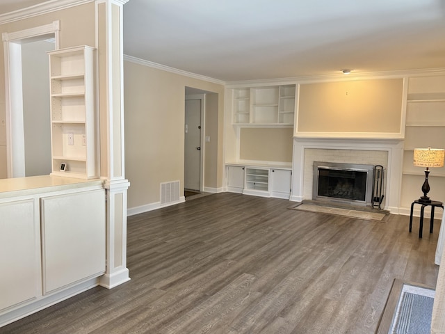 unfurnished living room featuring visible vents, dark wood-type flooring, ornamental molding, a brick fireplace, and baseboards