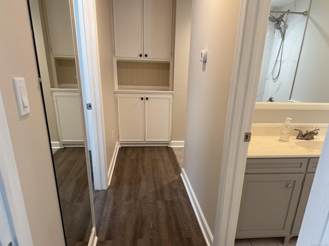 corridor featuring dark wood-type flooring, a sink, and baseboards