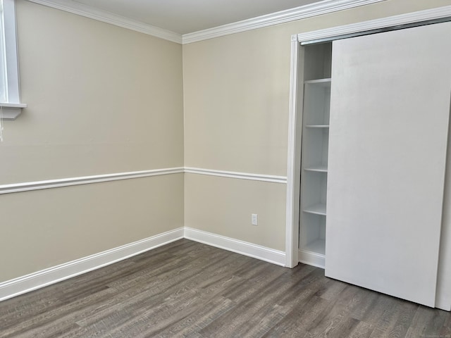 unfurnished bedroom featuring baseboards, ornamental molding, dark wood finished floors, and a closet