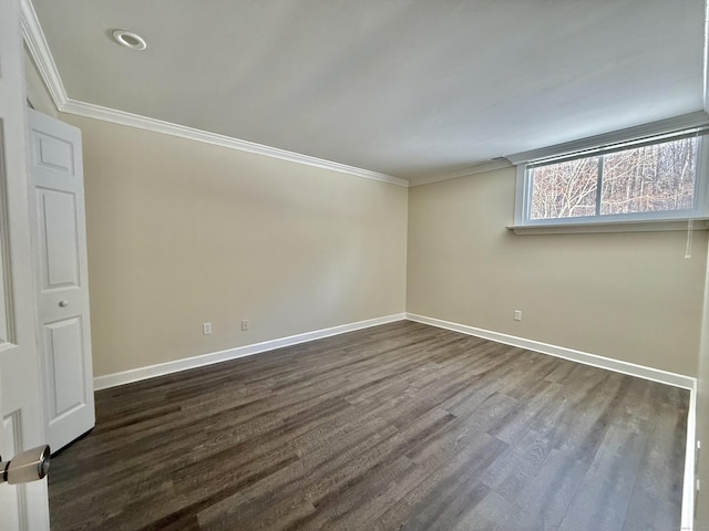 empty room featuring ornamental molding, dark wood-type flooring, and baseboards