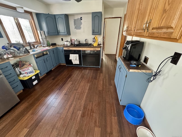 kitchen featuring sink, dark wood-type flooring, black oven, and blue cabinetry