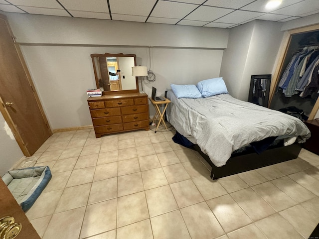 bedroom with a closet, a paneled ceiling, and light tile patterned floors