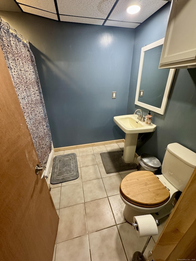 bathroom featuring a drop ceiling, tile patterned flooring, and toilet