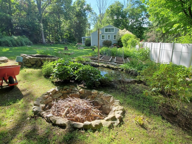 view of yard featuring a fire pit, a vegetable garden, and fence