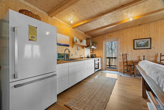 kitchen with wooden ceiling, oven, a sink, freestanding refrigerator, and beamed ceiling