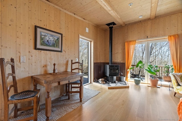 dining area with a wood stove, wood ceiling, wood finished floors, and beamed ceiling