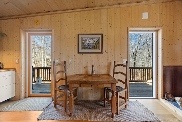 dining room with wood walls, wood ceiling, and light wood-style floors