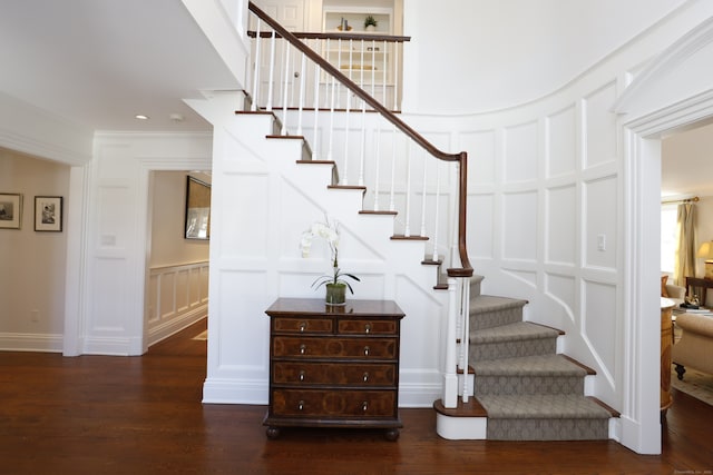 stairs with crown molding, a decorative wall, and wood finished floors