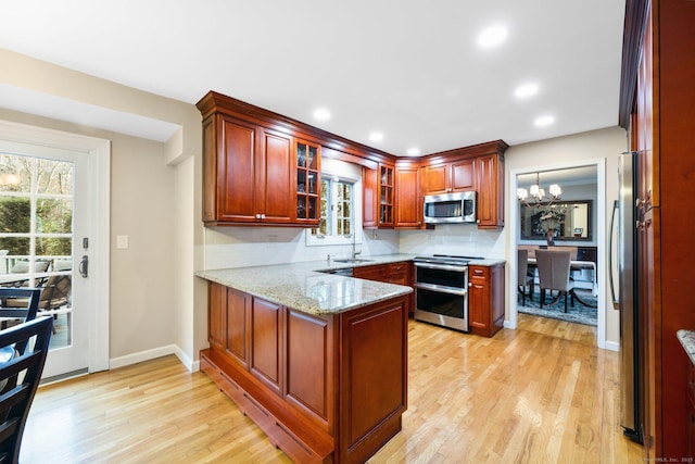 kitchen featuring stainless steel appliances, tasteful backsplash, glass insert cabinets, and light stone countertops