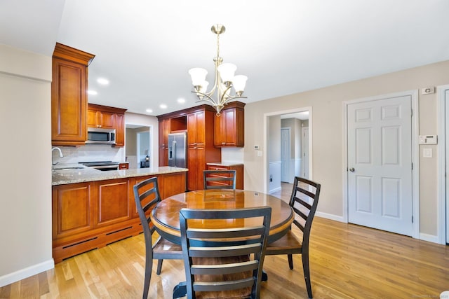 dining space with light wood finished floors, baseboards, a baseboard heating unit, and a chandelier