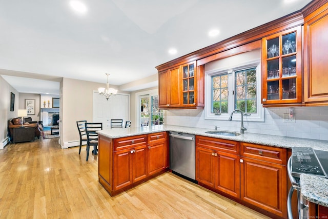 kitchen with glass insert cabinets, appliances with stainless steel finishes, a peninsula, hanging light fixtures, and a sink