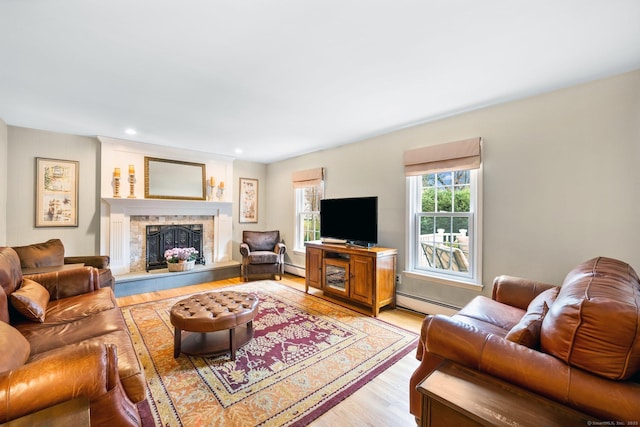 living room featuring light wood-type flooring, a baseboard heating unit, a fireplace with raised hearth, and recessed lighting